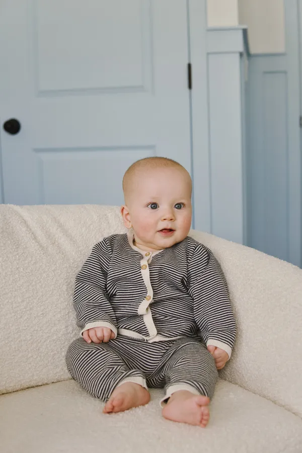 Baby sitting on a cozy chair with a soft blue door in the background