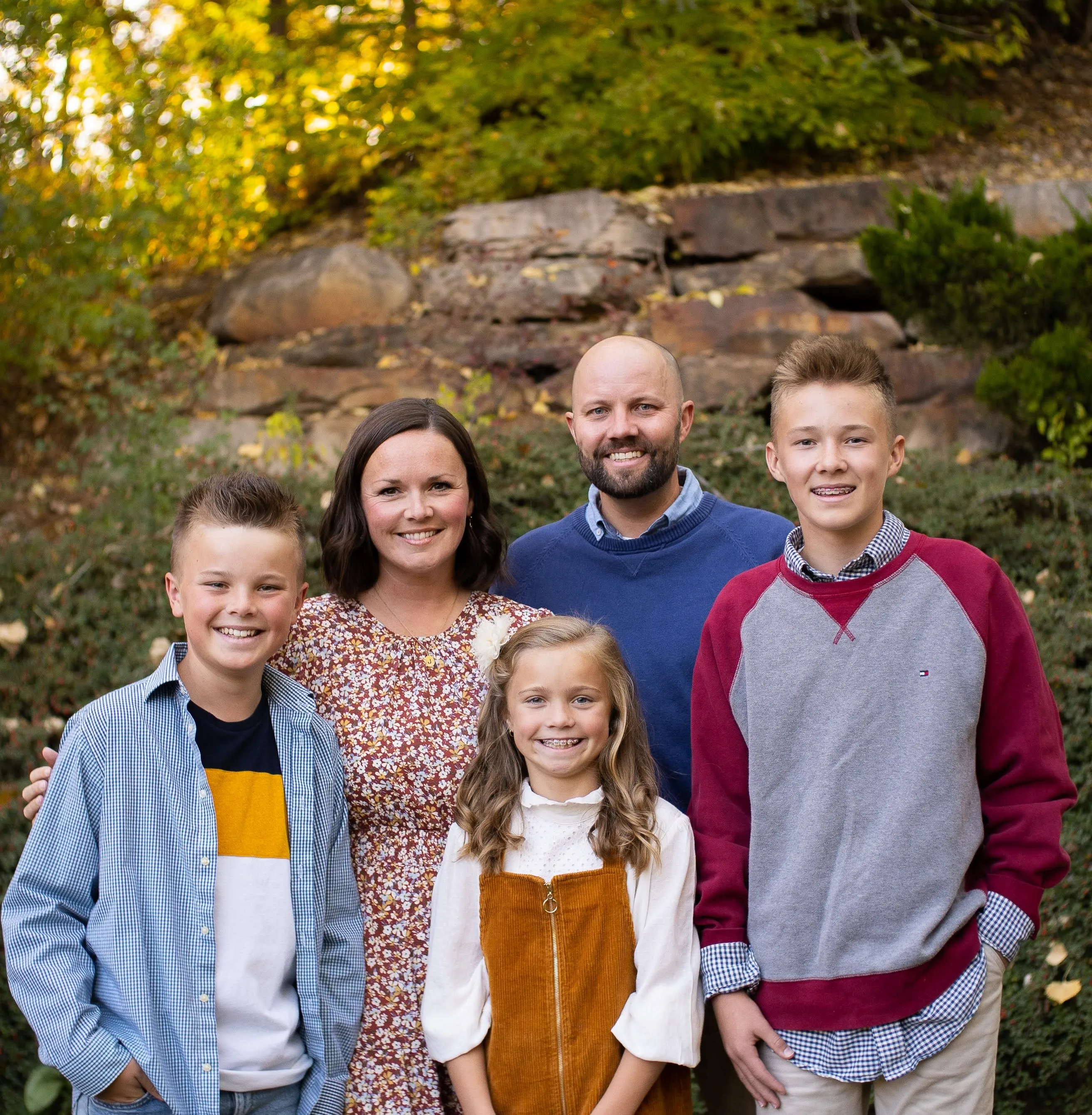 Family posing together outdoors during autumn, surrounded by fall foliage
