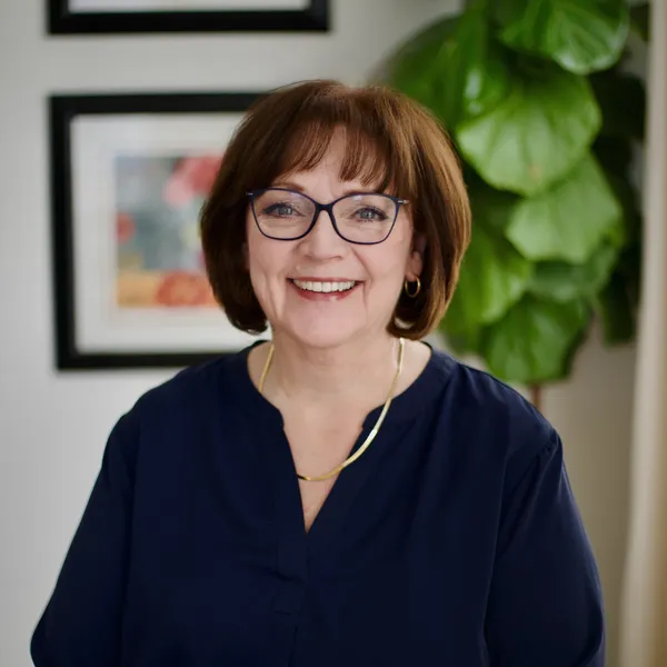 Professional headshot of a woman smiling warmly in an indoor setting