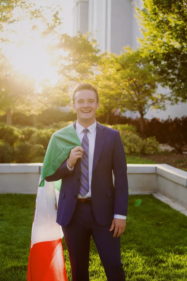 Young man in a navy suit holding a flag in beautiful golden hour light