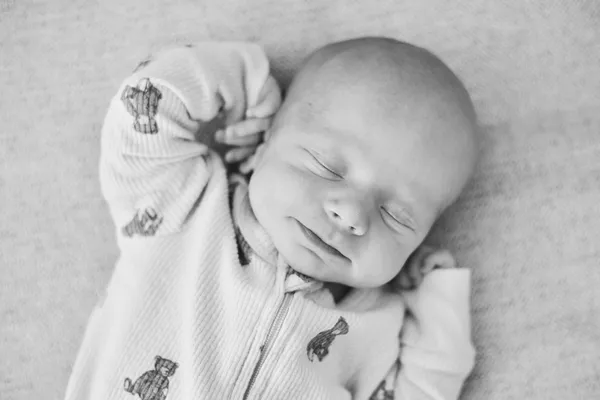 Newborn sleeping peacefully with a gentle smile, black and white portrait